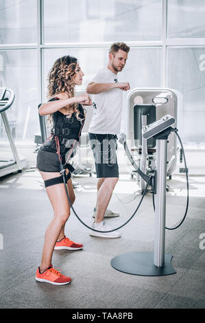 Electro stimulation EMS exercices femmes avec coach dans une salle de sport moderne. La stimulation électrique d'entraînement musculaire Banque D'Images