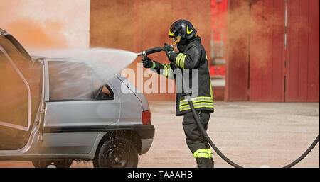 Au cours de la mousse des pompiers utilise un accident de la route sur la voiture cassée Banque D'Images