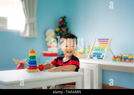 Tout-petits Asie adorable baby boy sitting on chair et en jouant avec des jouets de couleur à la maison. Banque D'Images