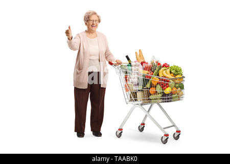 Portrait of a smiling woman posant avec un panier plein de nourriture et showing Thumbs up isolé sur fond blanc Banque D'Images