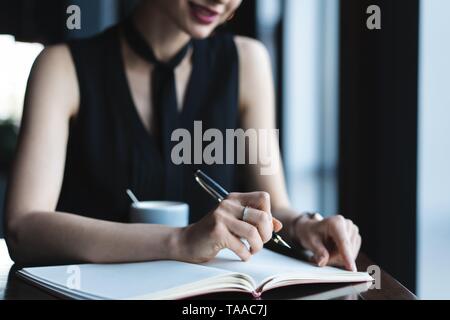 Femme comptable contrôle de la paperasse tout en restant assis près de fenêtre dans creative office ou d'un café. Certain jeune femme travaillant avec des documents. Banque D'Images