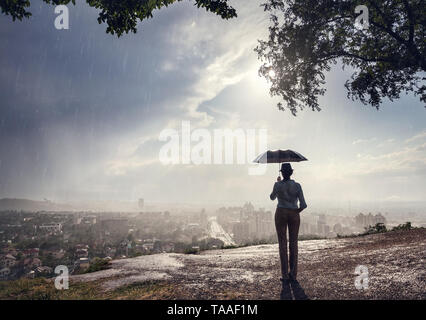 Silhouette de femme avec parapluie de la rue avec vue sur la ville de panorama spectaculaire des pluies soir . Vintage, style rétro. Banque D'Images