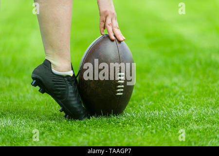 Ballon de rugby avec ses pieds sur la pelouse Banque D'Images