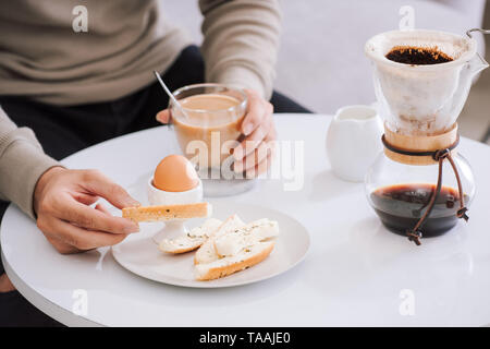 Délicieux petit-déjeuner frais avec un oeuf mollet, croustillant de pain grillé et de café dans la salle de séjour Banque D'Images