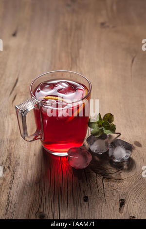 Boisson glacée de l'été - hibiscus thé froid avec de la glace et la menthe. Tasse de thé froid hibiscus avec de la glace, citron et menthe sur fond de bois vintage Banque D'Images