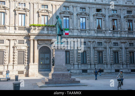 Milan, Italie - 23 mai 2019 : Les gens sont wolking le matin au square de San Fedele, statue de l'écrivain Alessandro Manzoni avec le drapeau italien i Banque D'Images