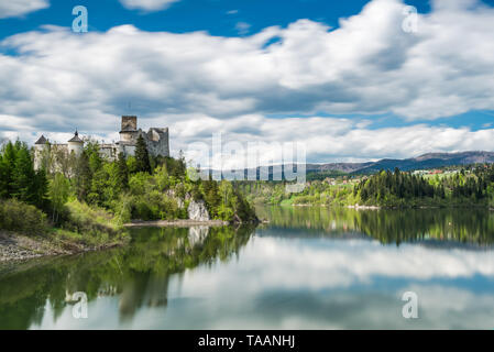 Le château de Niedzica sur hill top, lond de flou de l'exposition au lac Czorsztyn et nuages sur ciel. Banque D'Images