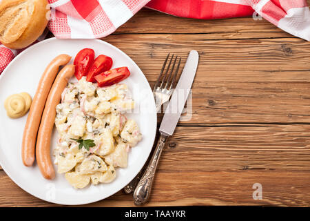 La salade de pommes de terre et les saucisses sur une vieille table en bois rustique (la nourriture allemande) Banque D'Images