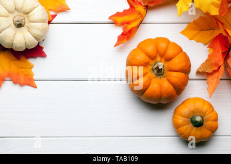 Les citrouilles avec des feuilles et une table en bois blanc Banque D'Images