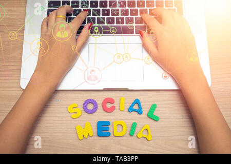 Femme d'affaires la main à l'aide d'un ordinateur portable avec les médias sociaux social media concept , lettres Banque D'Images
