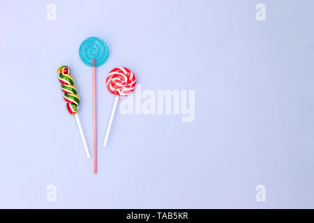 Bonbons sucette spirale colorés sur fond bleu. Concept minimal avec l'exemplaire de l'espace. Mise à plat. Banque D'Images