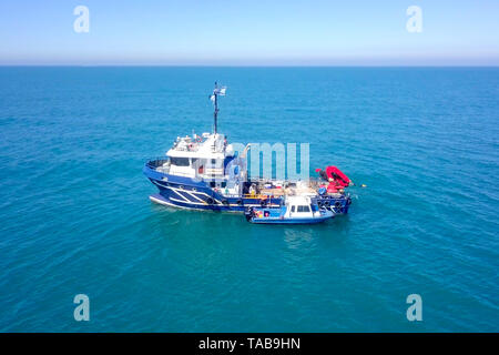 Bateau de pêche en mer avec un plus petit bateau amarré à côté - Vue aérienne de l'image. Banque D'Images