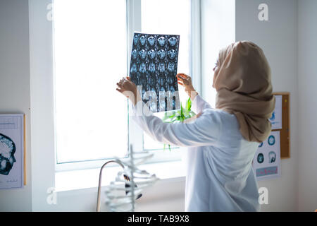 À la recherche de x-ray. L'expérience professionnelle médecin portant le hijab à la x-ray à fenêtre, debout près de Banque D'Images