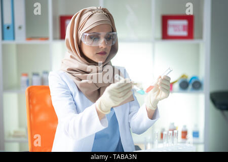 Jeune femme chimiste. Les jeunes femmes foulard chimiste et ganté holding test tube Banque D'Images