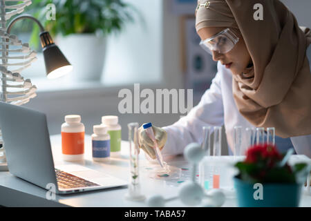 Laboratoire chimique. Femme portant le hijab travaillant dans le laboratoire chimique l'étude des agents chimiques Banque D'Images