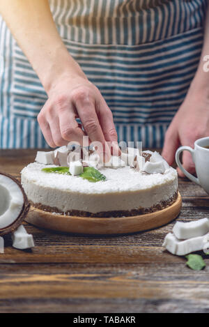 La noix de coco gâteau pâtissier décore brut avec de la pâte blanche et la menthe sur fond de bois. L'été frais et sain dessert vegan. L'alimentation sans gluten et sans sucre Banque D'Images