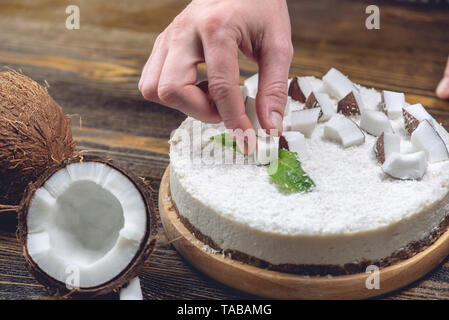 La noix de coco gâteau pâtissier décore brut avec de la pâte blanche et la menthe sur fond de bois. L'été frais et sain dessert vegan. L'alimentation sans gluten et sans sucre Banque D'Images