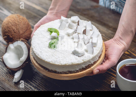 La noix de coco gâteau pâtissier décore brut avec de la pâte blanche et la menthe sur fond de bois. L'été frais et sain dessert vegan. L'alimentation sans gluten et sans sucre Banque D'Images