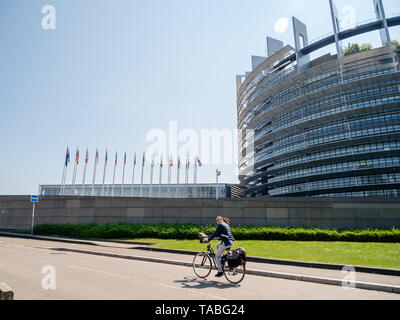 Strasbourg, France - 23 mai 2019 : femme adulte sur vélo avec Parlement Européen Bâtiment siège en arrière-plan tous les membres de l'UE membres drapeaux flottant