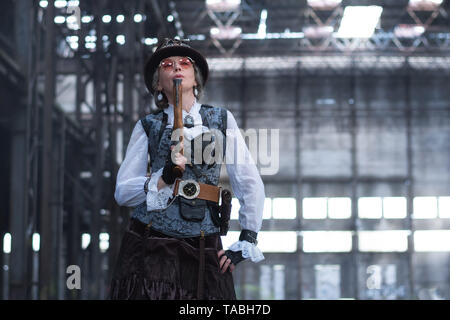 Dame âgée dans un costume steampunk dans une usine abandonnée les armes à la main. Banque D'Images