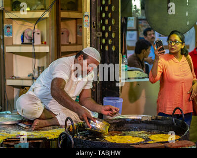 Mumbai, Inde - 11 mai 2019 : les fournisseurs Musulmans mâles vente cuisson des aliments halal et des collations fried pancake Malpuas route de caler au marché nocturne dans Banque D'Images