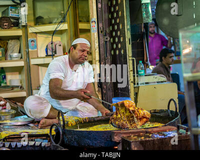 Mumbai, Inde - 11 mai 2019 : les fournisseurs Musulmans mâles vente cuisson des aliments halal et des collations fried pancake Malpuas route de caler au marché nocturne dans Banque D'Images