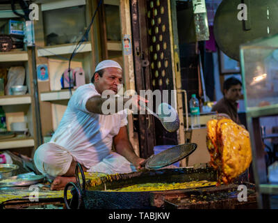 Mumbai, Inde - 11 mai 2019 : les fournisseurs Musulmans mâles vente cuisson des aliments halal et des collations fried pancake Malpuas route de caler au marché nocturne dans Banque D'Images