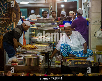 Mumbai, Inde - 11 mai 2019 : les fournisseurs Musulmans mâles vente cuisson des aliments halal et des collations fried pancake Malpuas route de caler au marché nocturne dans Banque D'Images