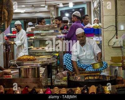 Mumbai, Inde - 11 mai 2019 : les fournisseurs Musulmans mâles vente cuisson des aliments halal et des collations fried pancake Malpuas route de caler au marché nocturne dans Banque D'Images