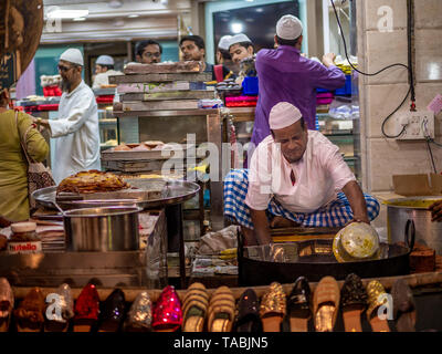 Mumbai, Inde - 11 mai 2019 : les fournisseurs Musulmans mâles vente cuisson des aliments halal et des collations fried pancake Malpuas route de caler au marché nocturne dans Banque D'Images