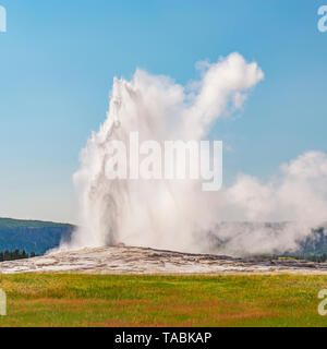 Photographie de la place Old Faithful Geyser lors d'une éruption par un beau jour d'été, le Parc National de Yellowstone, Wyoming, USA. Banque D'Images