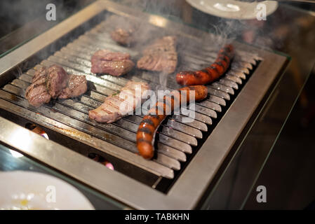 Différents types de viande de bœuf, des steaks et des saucisses de porc, cuits sur un barbecue piscine Banque D'Images