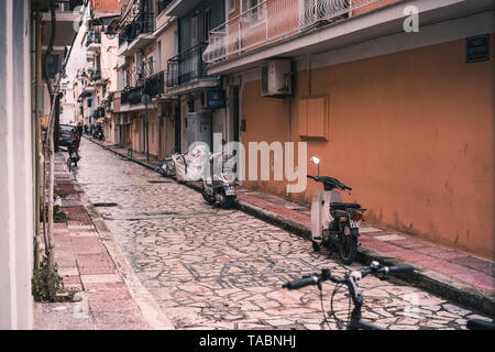 Zakynthos, Grèce - Avril 2019 : vélos et scooters debout entre les vieux immeubles sur rue piétonne étroite dans la ville de Zakynthos Banque D'Images