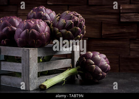 Graden violet frais artichauts en boîte en bois. Banque D'Images