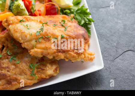 Deux épais filets de colin, Pollachius pollachius, qui ont été en grande friture pâte fait maison et servi avec des fruits et légumes crus. L'pollac Banque D'Images