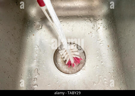 L'eau dans l'évier avec brosse de nettoyage Banque D'Images