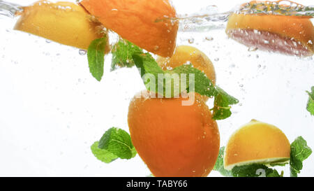 Libre de droit de couper les oranges juteuses frais avec les feuilles de menthe flottant dans l'eau claire contre fond blanc Banque D'Images