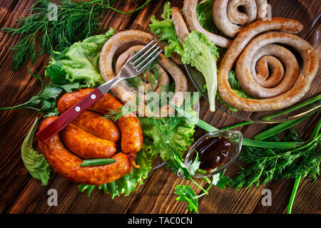 Saucisses grillées se situent sur une surface en bois avec les Verts : laitue, aneth, oignon et persil. Vue de dessus. Banque D'Images