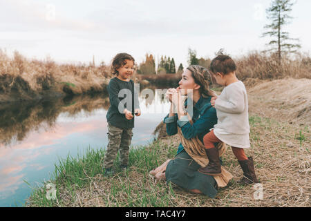 Maother et des enfants jouant avec un brin d'herbe à une rivière Banque D'Images