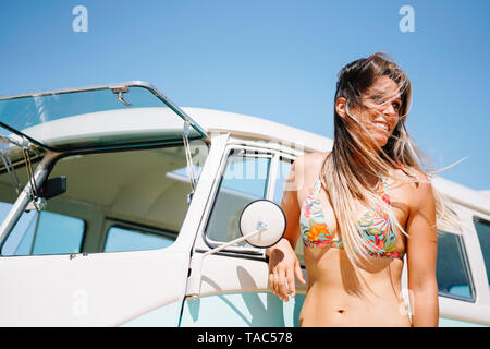 Pretty woman in a bikini appuyée contre un vieux transporteur Banque D'Images