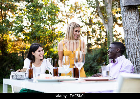 Hôte servant de la nourriture à un dîner d'été dans le jardin Banque D'Images