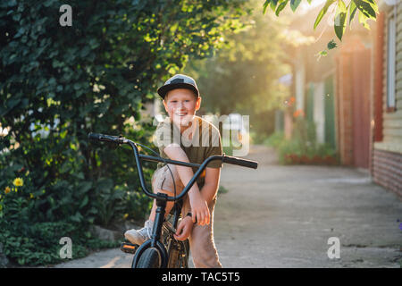 Portrait of smiling boy with vélo BMX sur route Banque D'Images