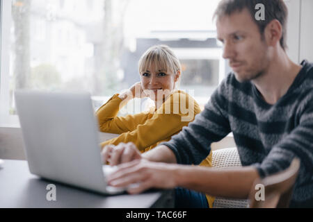 L'homme et la femme assis à table, using laptop Banque D'Images