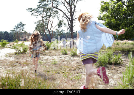 Vue arrière de deux jeunes filles qui traversent le paysage de dunes Banque D'Images