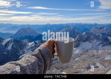 Allemagne, Bavière, Zugspitze, hand holding coffee mug dans paysage de montagne Banque D'Images