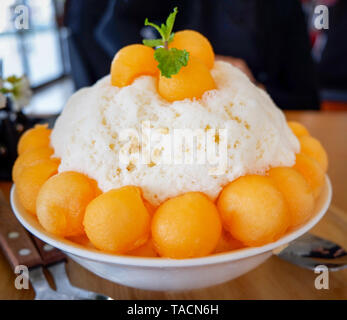 Corée style Bingsu dessert / bingsu bingsoo cantaloup bac sur table en bois - desserts sucrés fruits melon cantaloup rasée coréen sur la glace topping avec mil Banque D'Images