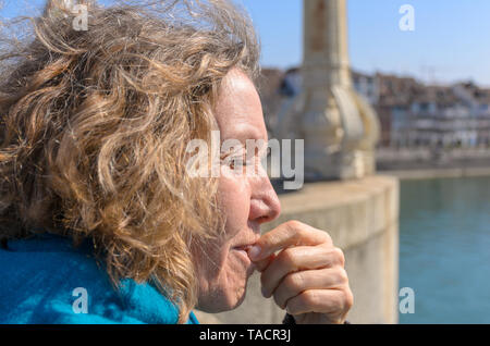 Middle-aged woman enjoying le soleil du printemps à l'extérieur debout sur un pont dans une ville avec ses yeux fermés dans un close up head shot Banque D'Images