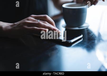 Close up of women's hands holding smartphone, femme à l'aide de téléphone mobile pendant la pause-café. Banque D'Images