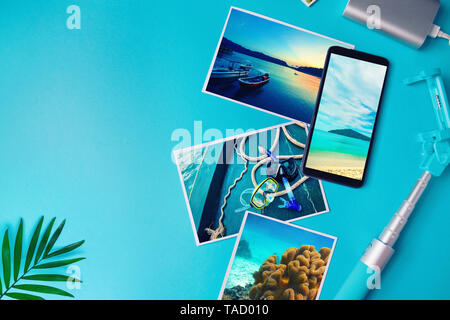 Smartphone avec photos des tropiques à l'écran, des photos avec des paysages et la mer depuis une location sur un fond bleu. Mise à plat. Banque D'Images
