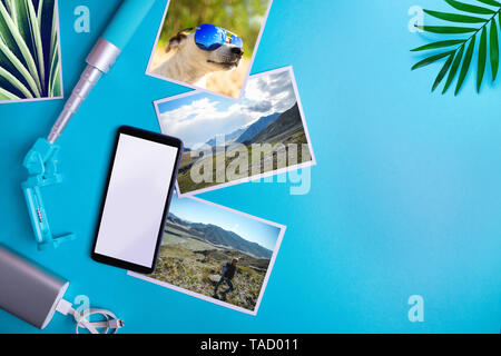 Concept de vacances d'été. Smartphone avec écran blanc et des dépliants et des photos sur un fond bleu. Maquette, mise à plat Banque D'Images